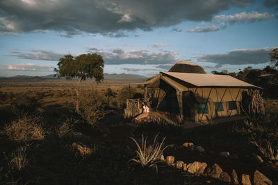 Woman sitting outside hut against sky