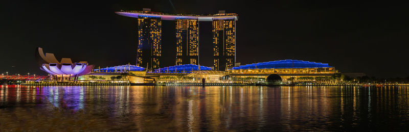 Illuminated building by river at night