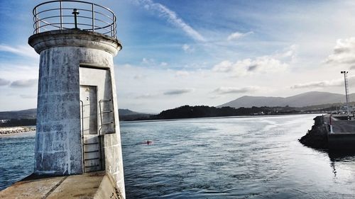 Lighthouse by sea against sky