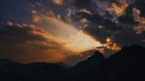 Scenic view of silhouette mountains against dramatic sky