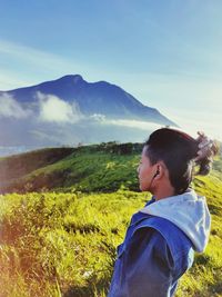 Side view of man looking at mountains against sky