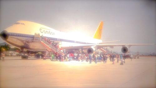 Airplane at airport runway against sky