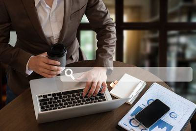 Midsection of man using smart phone on table