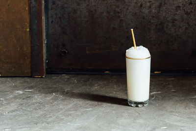 Ramos gin fizz milkshake cocktail with tall foam and gold straw on concrete 