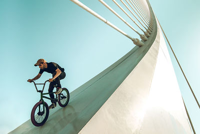 Low angle view of man riding bicycle on built structure against sky