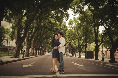 Young couple standing on road along trees