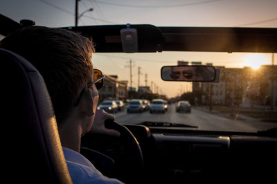 Young man driving car on street at dusk