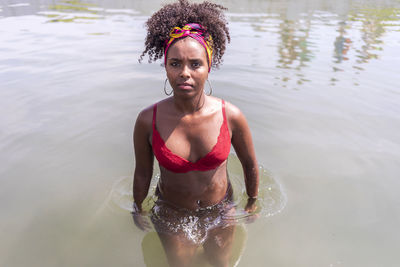 Portrait of young woman wearing bikini while standing in lake