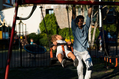 Girl with man swinging in playground