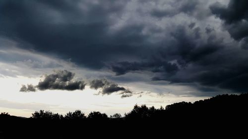 Silhouette trees against cloudy sky