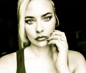 Portrait of woman eating face against black background