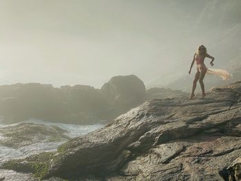 Young woman on rock against sky