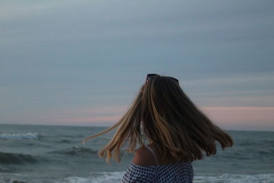 Rear view of woman at beach against sky