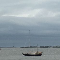 Boats in sea against cloudy sky