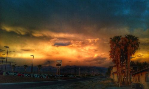 Scenic view of road against cloudy sky at sunset