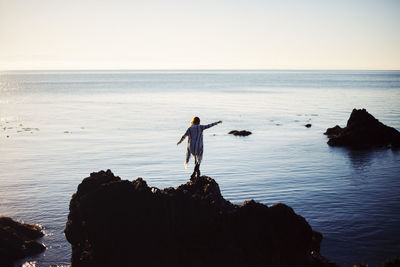 Rear view of man standing on rock at beach