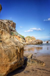 Scenic view of rocky beach against blue sky