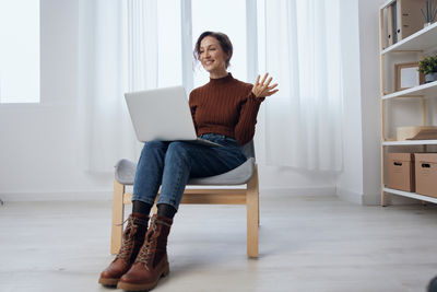 Full length of woman sitting on sofa at home