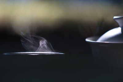 Close-up of smoke emitting from cigarette on table