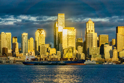 The setting sun makes a section of the city of seattle shine across elliott bay.