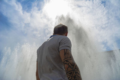 Rear view of man standing by fountain against sky