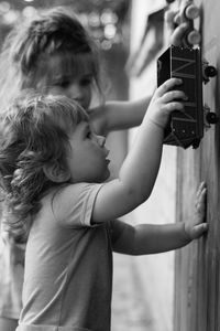 Siblings playing with toy cars on wall