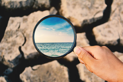 Close-up of hand holding sea against sky