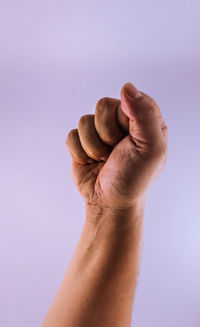 Close-up of hand gesturing fist against purple background
