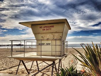 Information sign on sea shore against cloudy sky