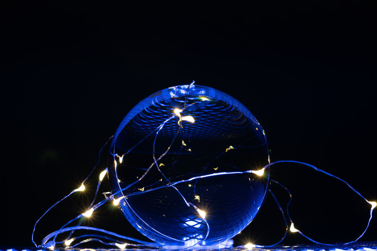 CLOSE-UP OF ILLUMINATED LIGHT BULBS AGAINST BLACK BACKGROUND