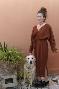 Teenage girl with dog standing against wall