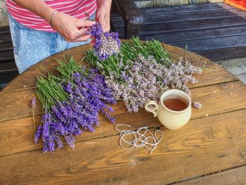 High angle view of woman holding purple flower on table
