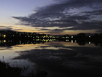 Scenic view of lake against cloudy sky at sunset