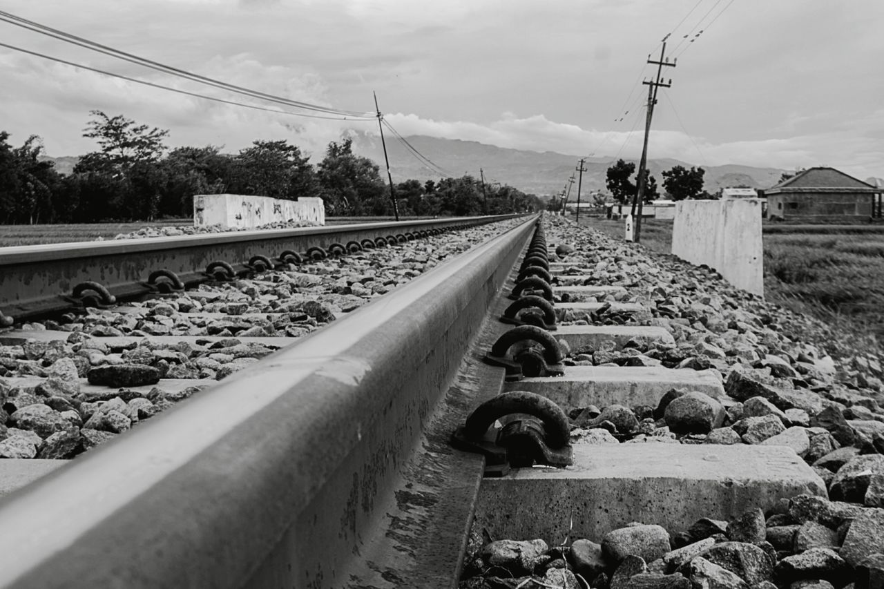 transportation, rail transportation, sky, railroad track, track, mode of transportation, nature, cloud - sky, day, metal, no people, the way forward, direction, electricity, diminishing perspective, cable, train, gravel, solid, train - vehicle, outdoors, straight, surface level, power supply