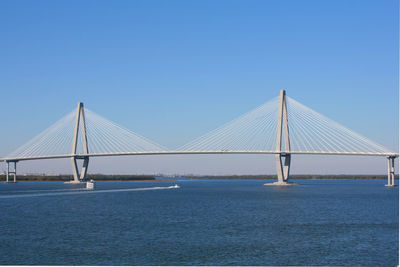 Suspension bridge over sea against clear blue sky