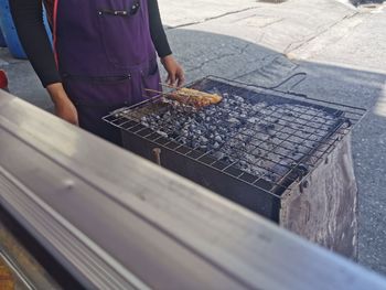 Midsection of woman standing by barbecue grill outdoors