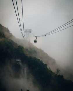 Low angle view of overhead cable car against sky