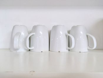 Close-up of white cups on shelf