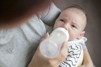 Cropped image of mother feeding milk to baby boy