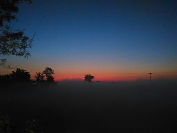 Scenic view of silhouette field against clear sky at sunset