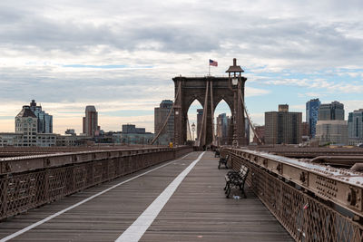 Bridge over buildings in city against cloudy sky