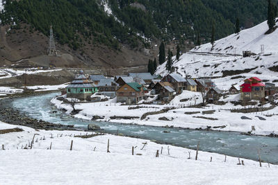 Snow covered houses by buildings against mountain