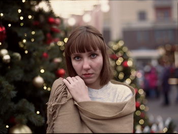 Close-up portrait of young woman against christmas tree