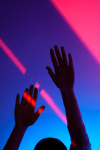 Close-up of hand on illuminated light against blue sky