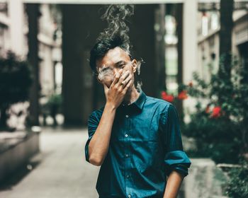 Portrait of man smoking cigarette while standing outdoors