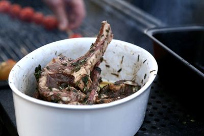 High angle view of meat in bowl standing outdoors on the grill waiting to be grilled 