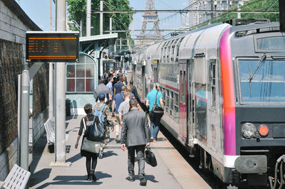 People at station with train against eiffel tower