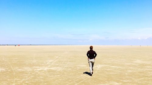 Full length rear view of man standing on desert against clear sky