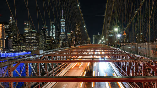 Light trails on bridge against buildings at night
