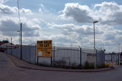 Road sign by street against sky in city